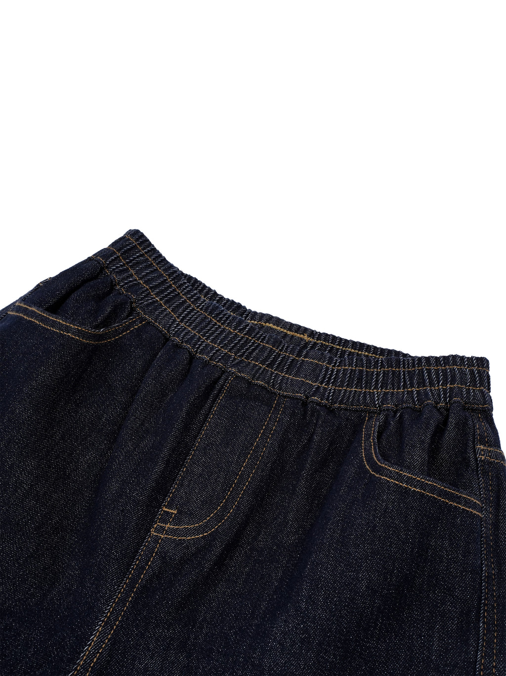 Close-up of dark indigo denim pants showing the elastic waistband, front pocket, and contrast stitching against a white background.