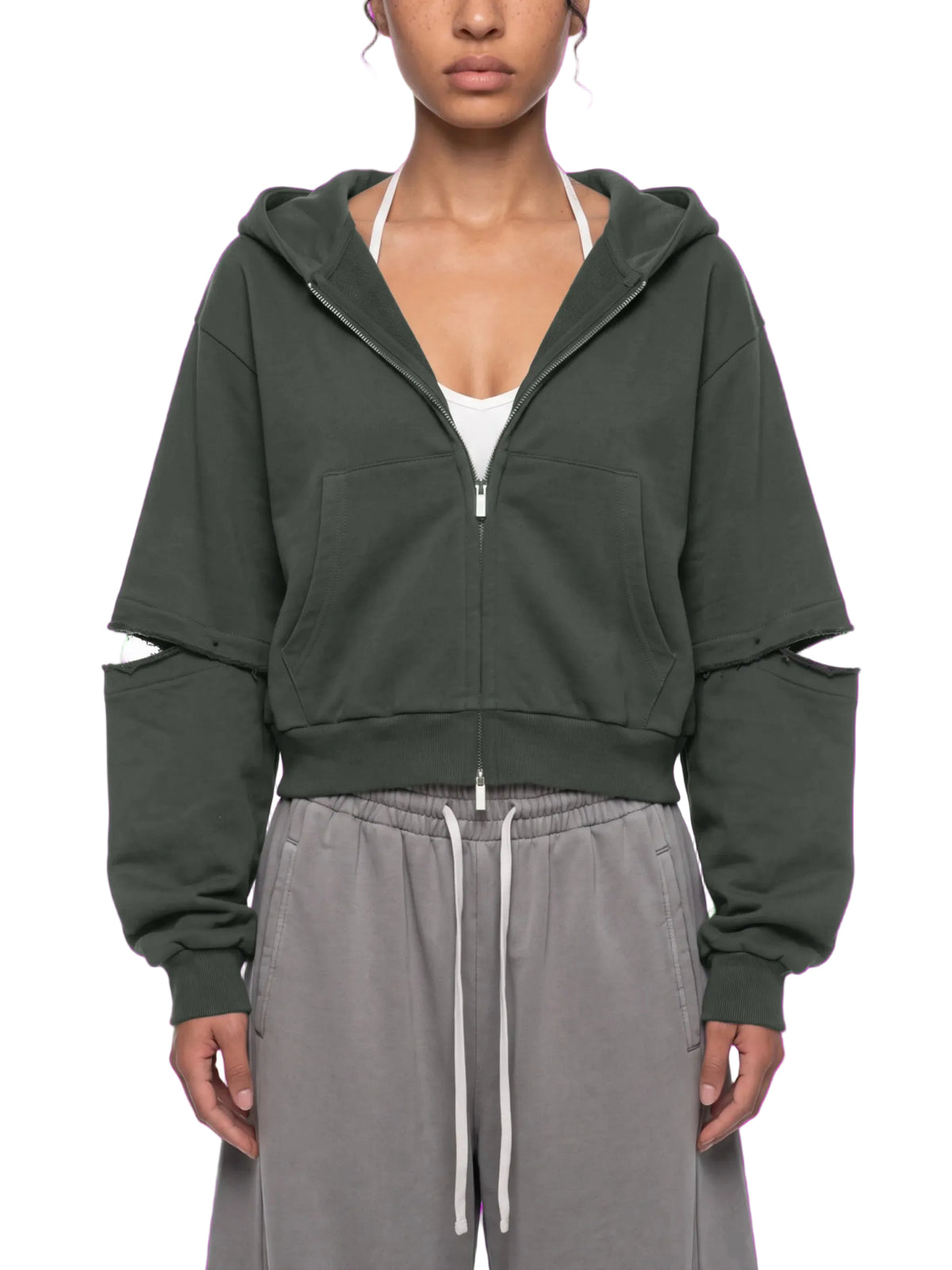 A model wearing a dark olive green cropped zip-up hoodie with distressed details on the sleeves, styled with gray drawstring sweatpants against a white background.